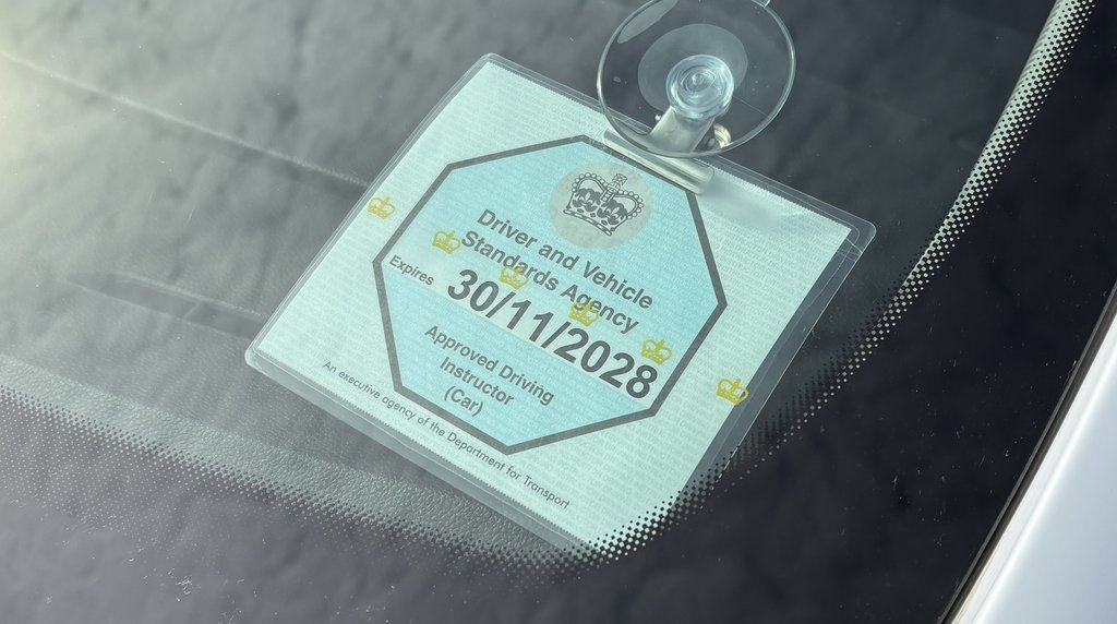 Approved driving instructor badge displayed in a car windscreen